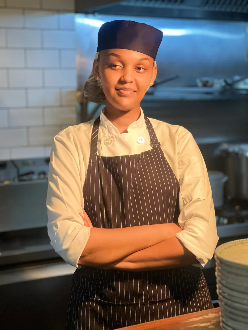 Chef Kersy in the kitchen, arms crossed, smiling